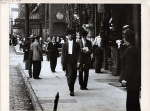 Pedestrians on the sidewalk in front of New Lindell Hotel and Fellhauer Wine shop at 705 6th Street and 707 6th Street